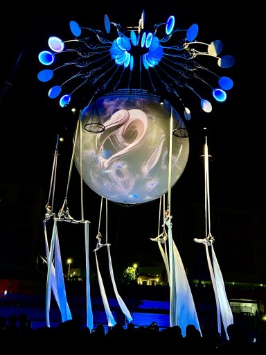 spectacle de rue Installation artistique nocturne avec une sphère illuminée et des drapés, créant une ambiance mystique.