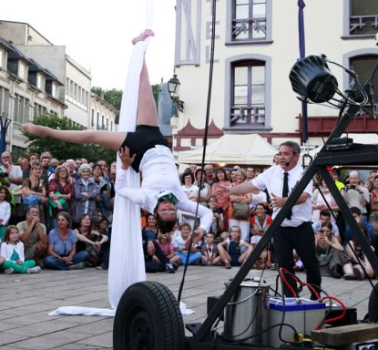 spectacle déambulation allégorie de la grenouille Artiste équilibriste en costume blanc, exécutant un numéro acrobatique devant une foule.