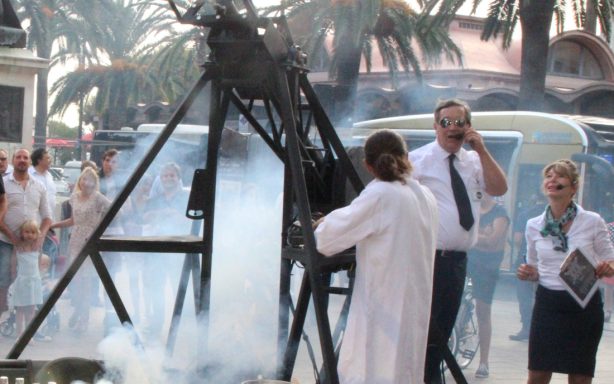 spectacle de rue, déambulation Un homme en blouse blanche opère une machine, entouré de spectateurs et de fumée.