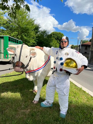 allegorie de la grenouille Un homme en tenue d'astronaute pose avec une vache décorée près de la route.