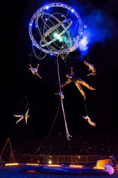 spectacle de cirque aérien Galileo Artistes acrobatiques suspendus dans les airs, entourés de lumières vives.