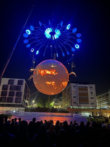 Spectacle Le Grand Mire Spectacle nocturne avec une sphère lumineuse et des feux d'artifice au-dessus d'une foule.