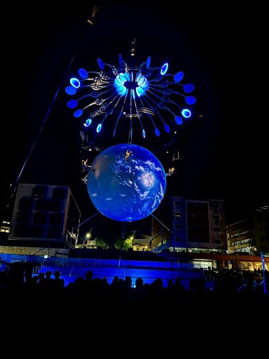 décor de spectacle Projection d'une Terre en apesanteur sous un ciel nocturne illuminé par des lumières bleues.