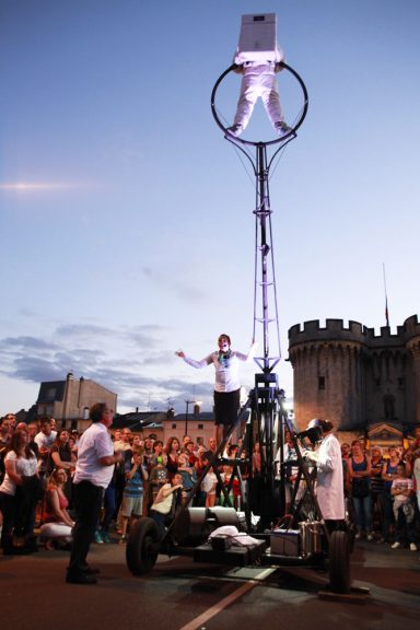 artiste de cirque Un artiste sur une plateforme élévée, entouré d'un public, devant un château.