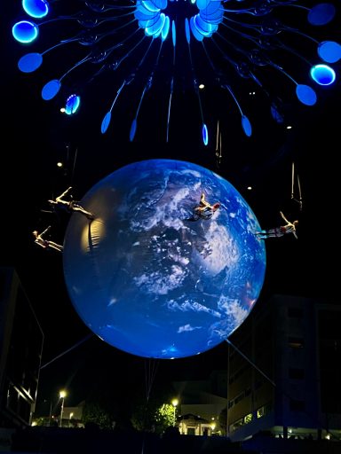 danse aerienne Globe lumineux représentant la Terre, suspendu avec des éléments lumineux au-dessus.
