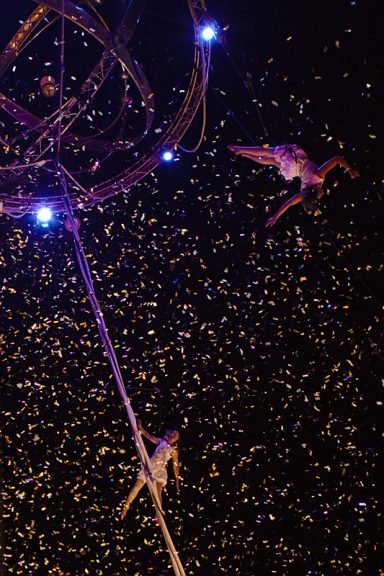 spectacle de confettis Des artistes acrobates se produisent sous un ciel étoilé, entourés de paillettes dorées.