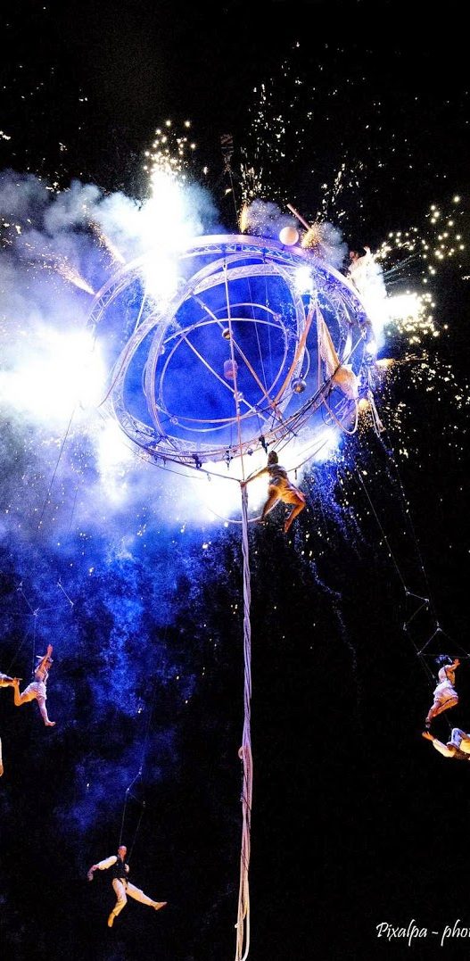 spectacle de rue Galileo Artistes de cirque exécutant des acrobaties autour d'une structure illuminée par des feux d'artifice.