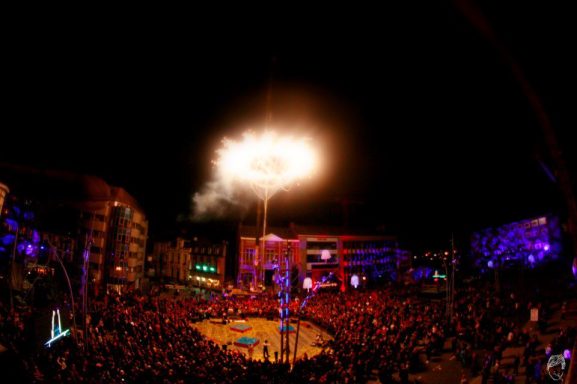 public des arts de rue Salle de concert illuminée avec un feu d'artifice au-dessus d'un public enthousiaste.