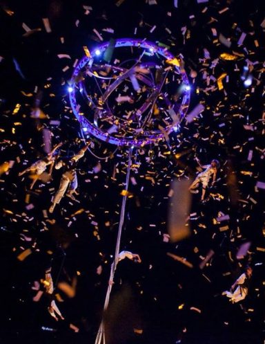 vol en harnais Des éclats colorés tourbillonnent autour d'un cerceau lumineux suspendu.