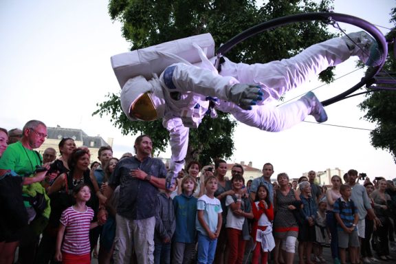 vol d'astronaute Un astronaute en apesanteur, entouré d'une foule admirative.
