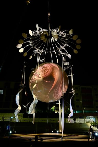 machinerie de scene Sculpture nocturne avec un globe lumineux et des éléments suspendus.