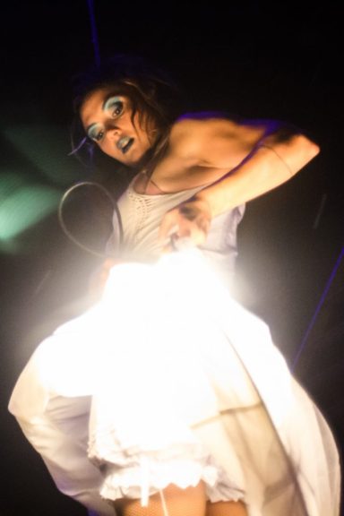 artiste acrobate Performeur en robe blanche brillante, avec des maquillages audacieux sur scène.