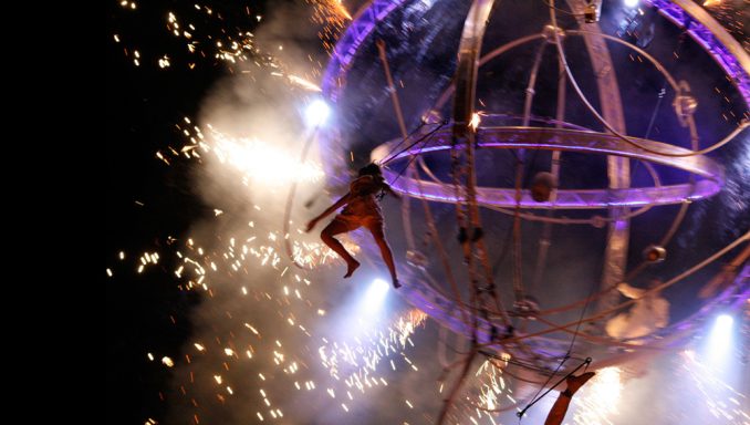 fête dans la rue Artiste acrobatique suspendu dans une sphère, entouré d'étincelles et de lumière.