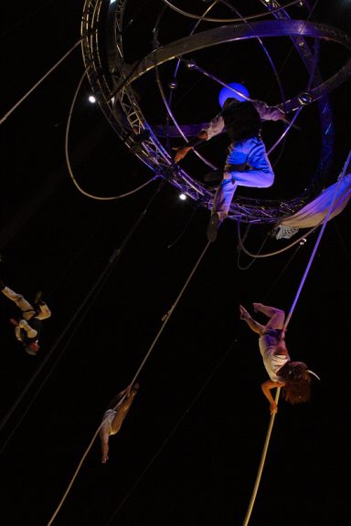 spanish rope performance Artistes de cirque s'élevant dans les airs, suspendus par des cordes, sur fond sombre.