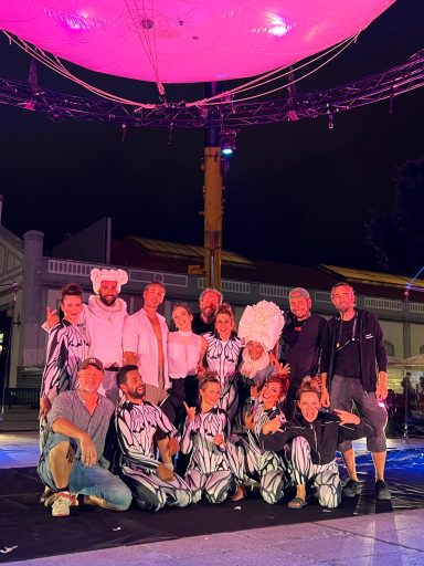 spectacle aérien le grand mire Groupe de personnes en tenue artistique sous un éclairage nocturne coloré.