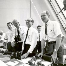 une equipe d'artistes Groupe d'hommes en chemises blanches, souriants, devant des caméras et des documents.