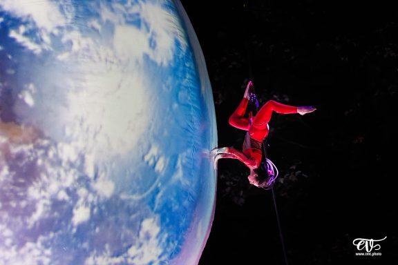 danse aerienne Un astronaute en combinaison rouge flotte dans l'espace près de la Terre.