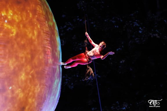 danse verticale Artiste acrobatique suspendu, évoluant près d'une grande planète colorée.