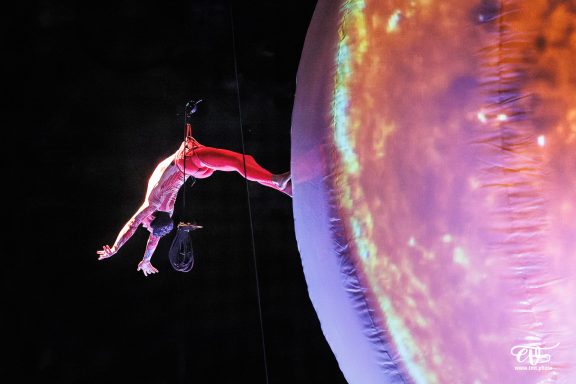 danseur aerien Artiste acrobate suspendu à une structure, exécutant un mouvement dynamique.