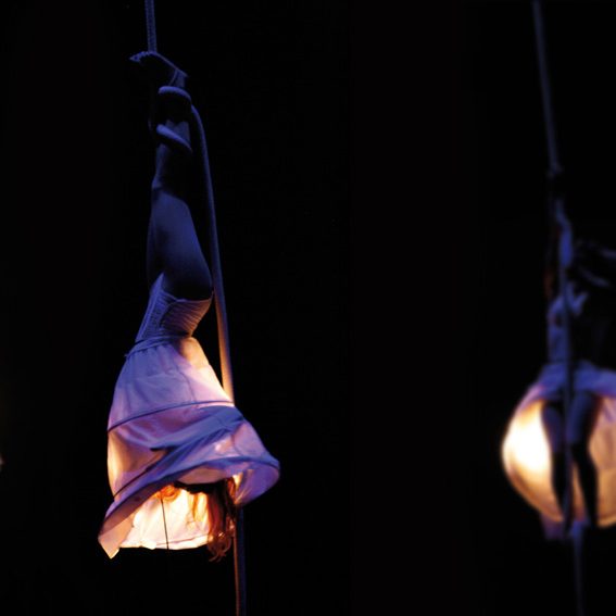 aerialist Danseuse en suspension, vêtue d'une robe blanche, éclairée par une lumière douce.