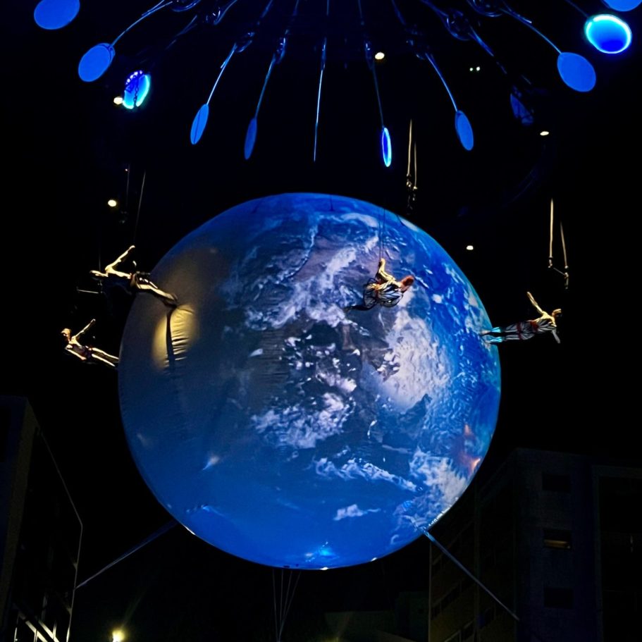 dans aérienne, danse sur batiments Globe stylisé projetant des images de la Terre, suspendu avec des éléments lumineux.