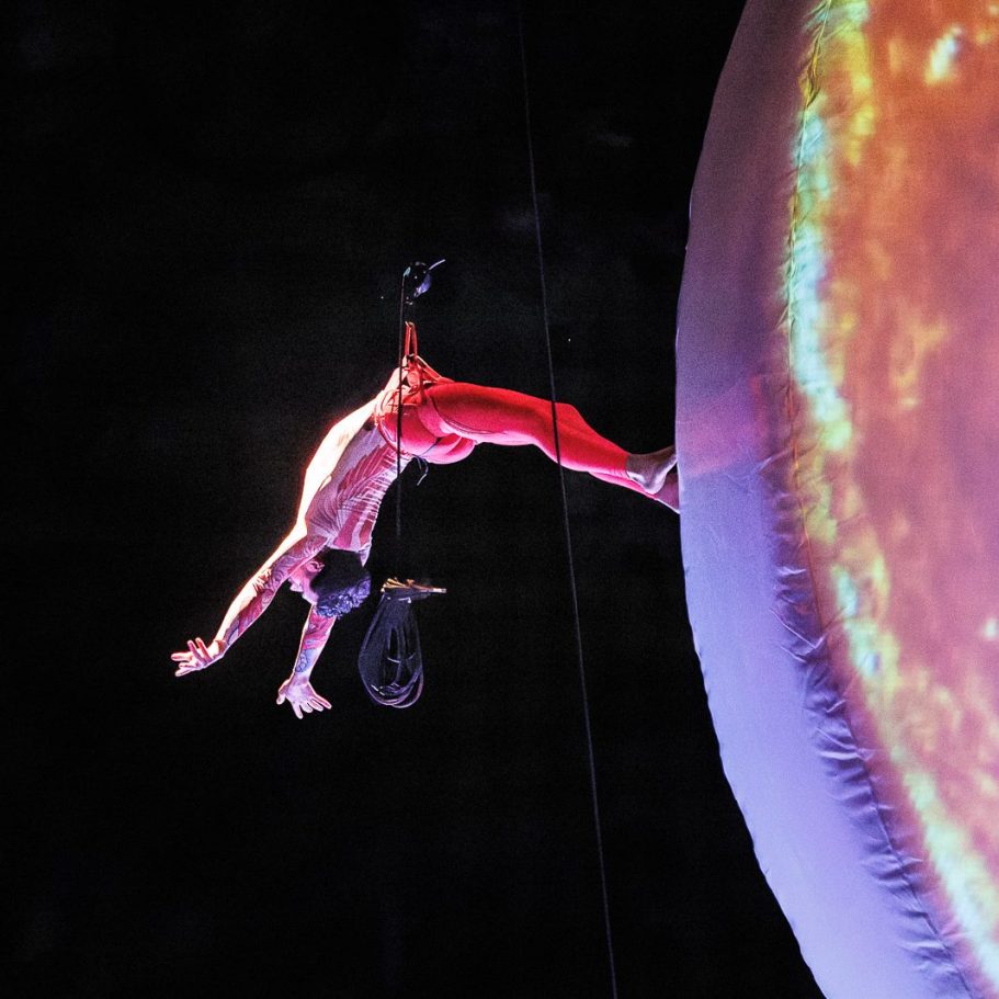 aerialist Un acrobate réalise une figure sur un immense globe coloré.