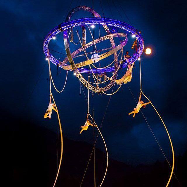 artistes aeriens Galileo Suspension artistique avec des acrobates en hauteur, éclairage par des lumières colorées.